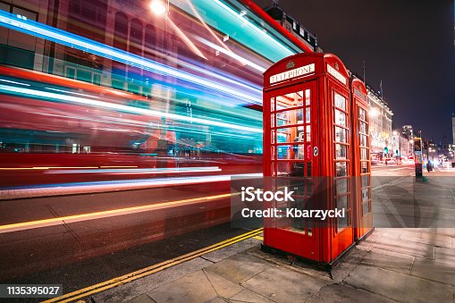 istock Light trails of a double decker bus next to the iconic telephone booth in London 1135395027