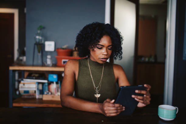 istock Young woman having a coffee in her apartment while browsing the web on tablet 1135396167