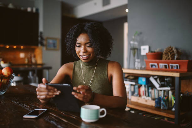 istock Young woman having a coffee in her apartment while browsing the web on tablet 1135396191