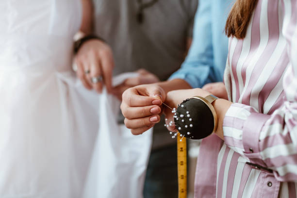 Close-up of needle cushion on tailor's hand. Taking measurements
