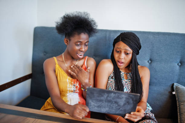 istock Two black african girlfriends at summer dresses in cafe 1135399497