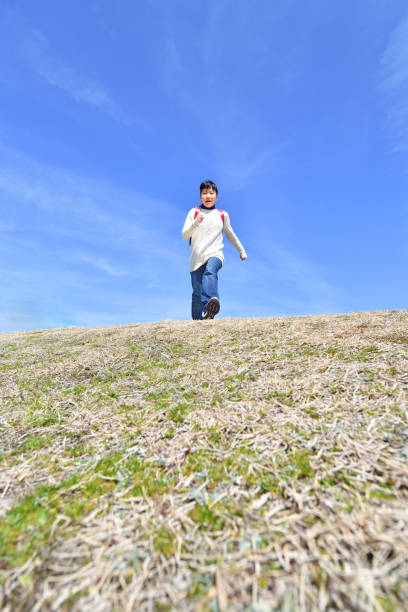 istock Japanese elementary school girl running in the blue sky 1135402530