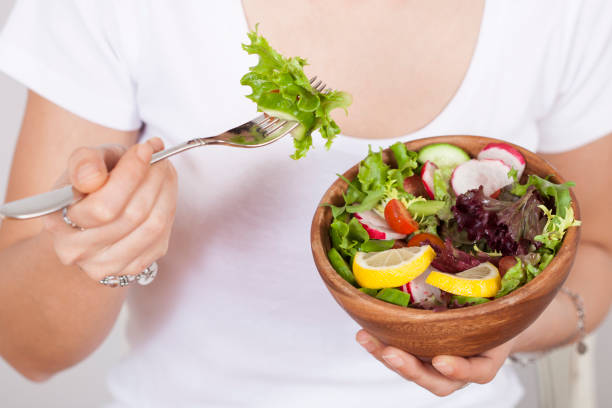 istock beautiful woman eating salad 1135406303
