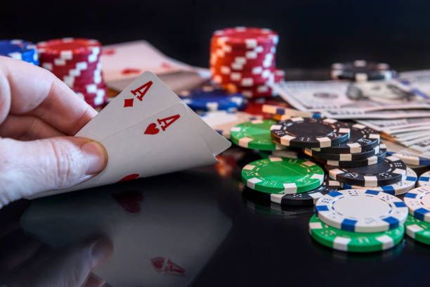istock Four aces in hand and gambling chips at black 1135408112