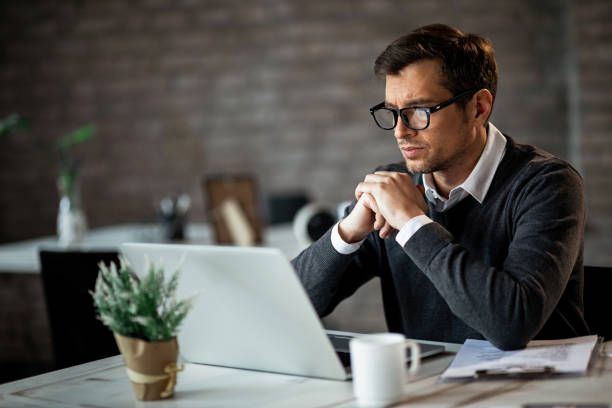 istock Serious businessman reading something on laptop while working in the office. 1135408392