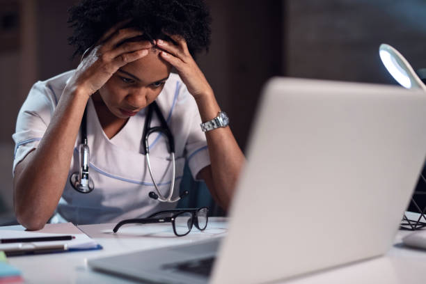 istock African American doctor having headache while reading an e-mail on laptop. 1135411117