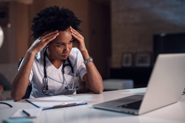 istock African American doctor having headache while reading an e-mail on laptop. 1135411695