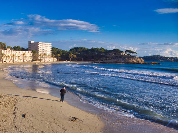 nice beach day in winter in mallorca woman walking at the desert beach in paguera, mallorca. seaside views of cala fornells mallorca stock pictures, royalty-free photos & images
