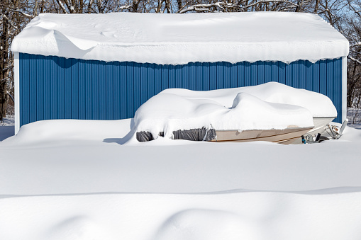 Two boats and a metal garage are covered with deep snow after a Minnesota blizzard.