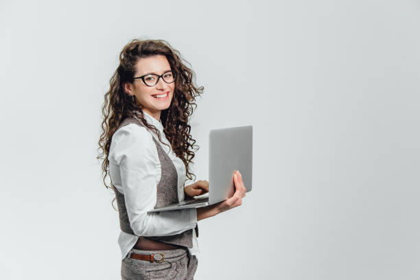 bbeautiful молодая девушка улыбается. работает на ноутбуке в очках и белой рубашке - holding laptop women computer стоковые фото и изображения