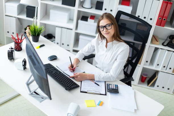 istock Young girl sitting at the table and working with a computer, documents and calculator 1135419690