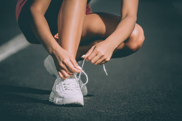 istock Woman's hand tying shoe laces at stadium. Preparation for running. Close up. Front view 1135420185