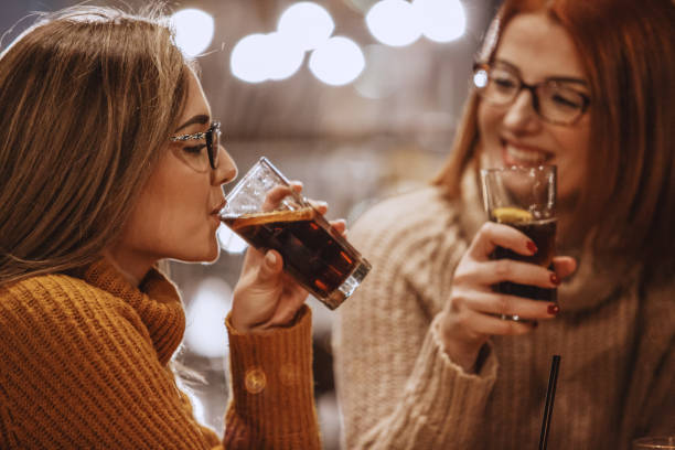Women drinking coke Close-up shot of two women having a refreshing drink at the bar. cold drink stock pictures, royalty-free photos & images
