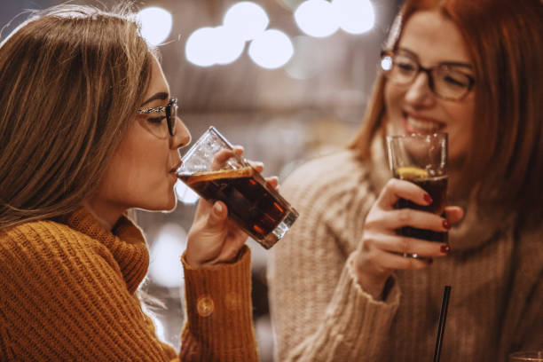 Women drinking coke Close-up shot of two women having a refreshing drink at the bar. non alcoholic beverage stock pictures, royalty-free photos & images