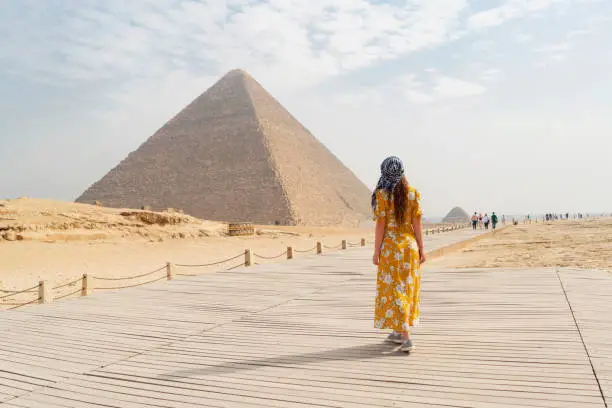 Rear view of a female tourist enjoying a tour to the Pyramids of Giza in Egypt.