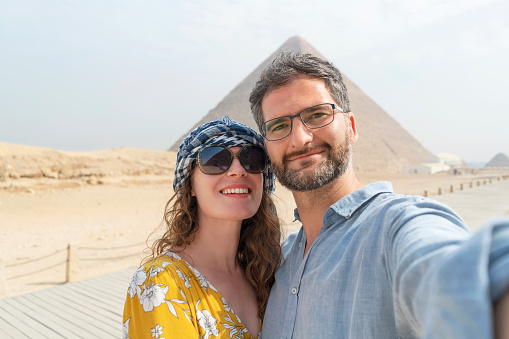 Caucasian couple taking selfie while visiting Pyramids of Giza in Egypt.