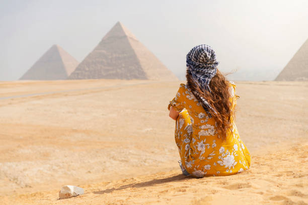 A World To Travel Rear view of a female tourist enjoying a tour to the Pyramids of Giza in Egypt. kheops pyramid photos stock pictures, royalty-free photos & images