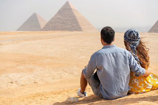 Rear view of a traveling couple visiting Pyramids of Giza in Egypt.