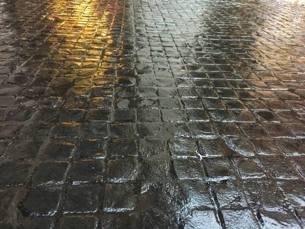 istock Wet dark brown stone tile on the floor. Lighting reflection on rough walkway surface. 1135448442
