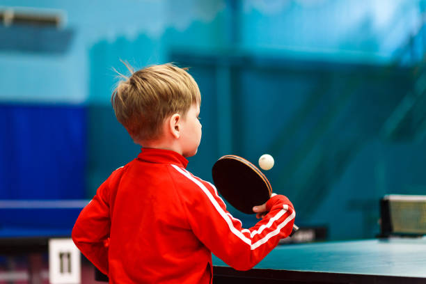 a child plays table tennis in the gym, a child beats a tennis ball