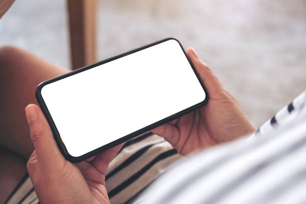 istock Mockup image of woman's hands holding black mobile phone with blank white screen horizontally in cafe 1135456752