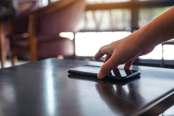 une main saisissant et ramassant le téléphone mobile sur la table - sonner photos et images de collection