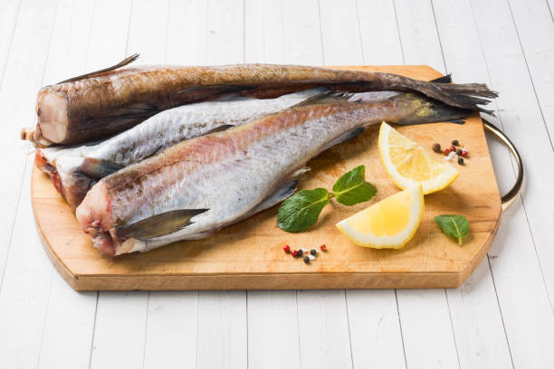 raw fresh pollock fish on a wooden board with lemon - pollock trawler imagens e fotografias de stock