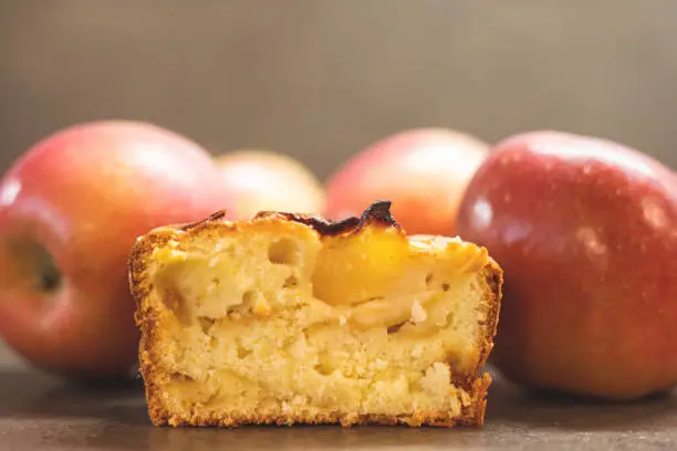 Closeup of an apple cake slice surrounded by fresh apples