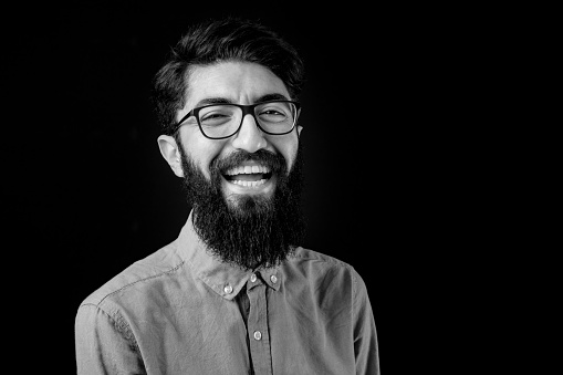 Black and white portrait of young bearded man with eyeglasses.