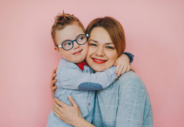 Tender feelings between mom and son with Down syndrome Family of Mom and son huging with tenderness. Down syndrome child smiling. down syndrome stock pictures, royalty-free photos & images