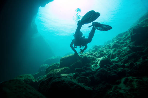 Scuba diver diving in area of underwater cave entrance