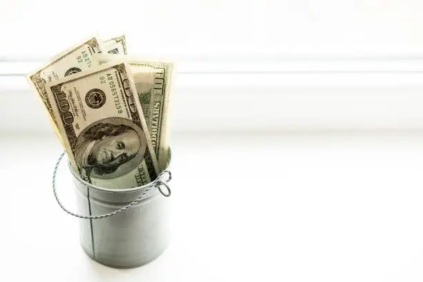 Moneybox, dollars in bucket on white window.light background. place for text. top view. a lot of money