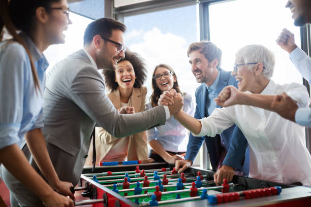 Business people having great time together.Colleagues playing table football in office. Business people having great time together.Colleagues playing table football in modern office. office competition stock pictures, royalty-free photos & images
