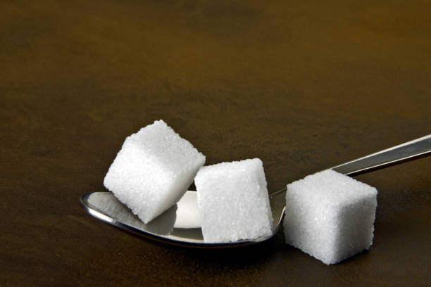 Close up of sugar cubes in a tea spoon, health awareness