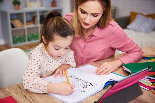 istock Young woman helping girl with homework 1135473701