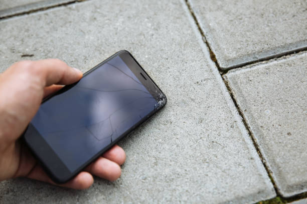 istock Ma is holding broken smartphone lying on the road outdoors. Crashed screen from the accidental fall. Fragile modern technologies. 1135476240