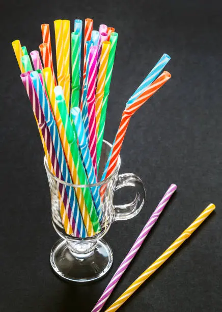 Colorful drinking straws in the glass on black background
