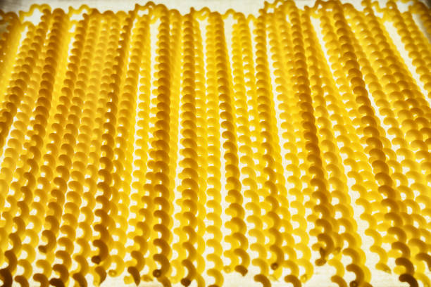 Italian pasta called fusilli , long thin corkscrew shaped pasta on a white cloth , beautiful light and shadows effect