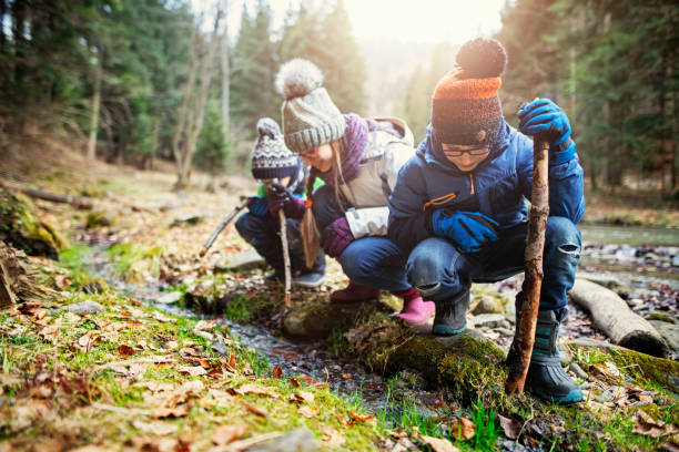 Photo of Happy kids hikers playing in stream with sticks