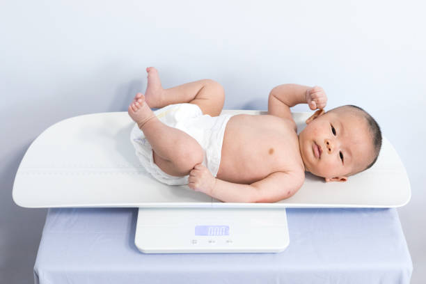 weighting baby  on scale - instrument of weight imagens e fotografias de stock