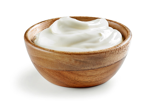 sour cream or yogurt in wooden bowl isolated on white background