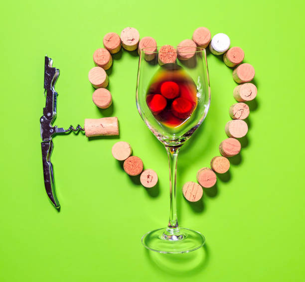 Glass of red wine ,corkscrew and cork stoppers forming a heart. wine love concept.