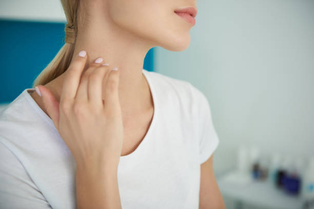 Cropped close up portrait of girl in white t-shirt keeping hand on her graceful neck