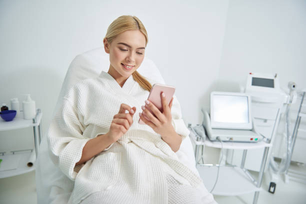 istock Beautiful young woman using cellphone in spa salon 1135483948
