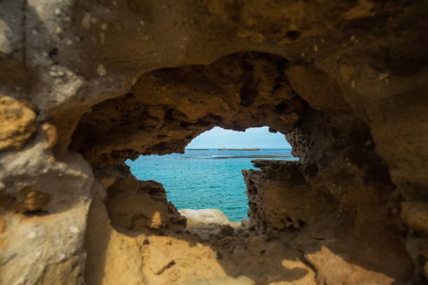 istock Sandstone rock with hole and blue sea in it 1135486177