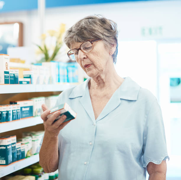 istock Senior female customer in pharmacy studies medication label 1135487570