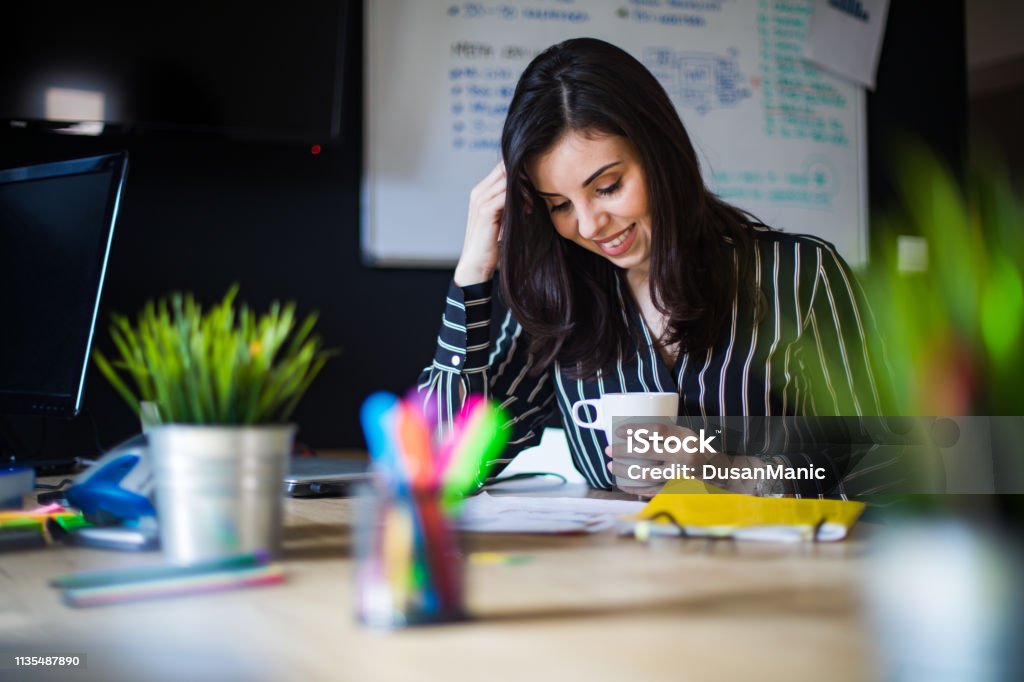 Portrait of confident business woman writing document sitting at workplace in office, copy space Publisher Stock Photo