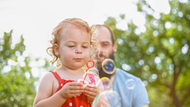 istock Little girl blowing soap bubbles 1135489080