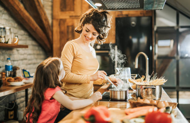 istock Happy mother and daughter talking while cooking lunch in the kitchen. 1135489340