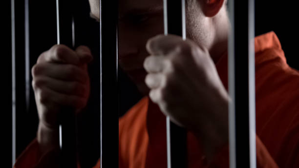istock Suspect in jail holding prison bars, awaiting trial, hoping to avoid punishment 1135489405
